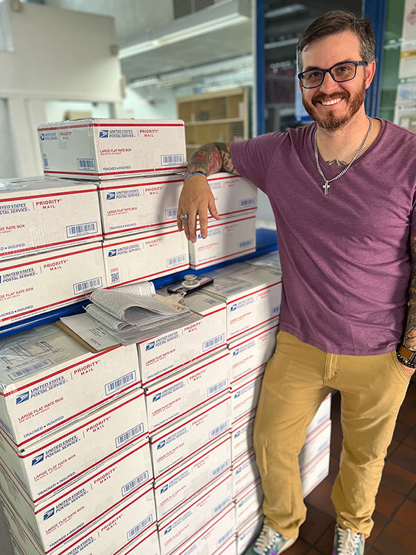 Justin Cavinder standing next to some of the boxes all packed and ready to boost morale.