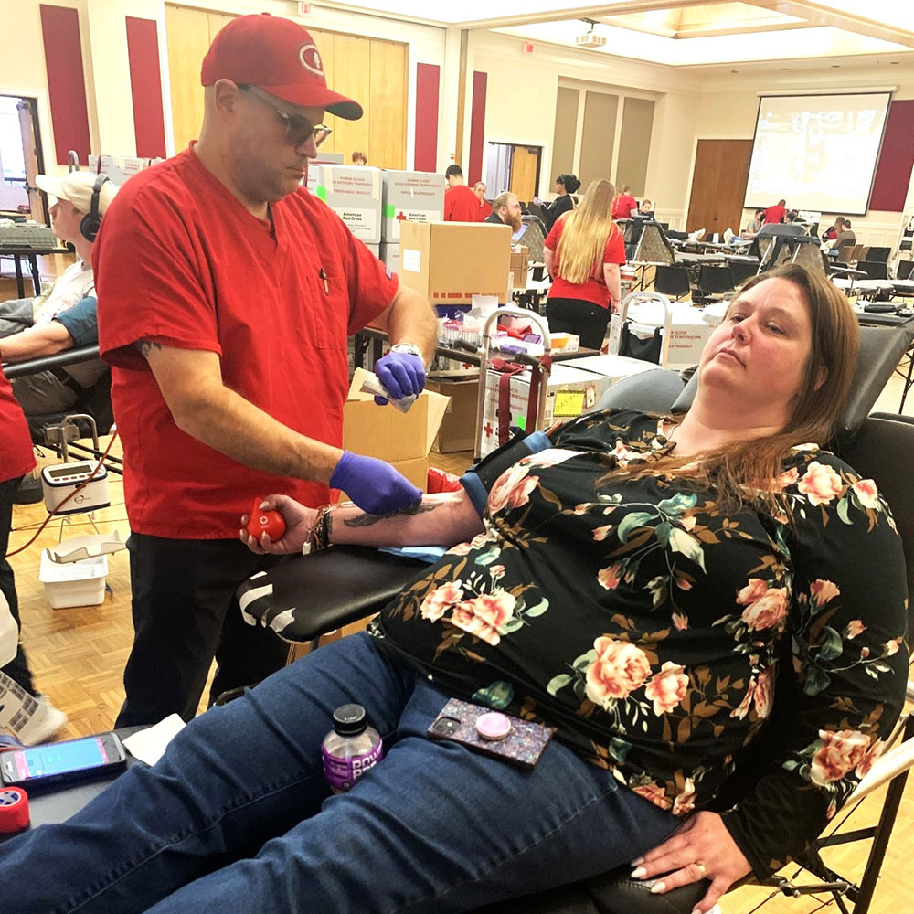 Amber Thomas sitting in a chair about to donate blood at the Red Cross blood drive. A Red Cross nurse is standing next to her.