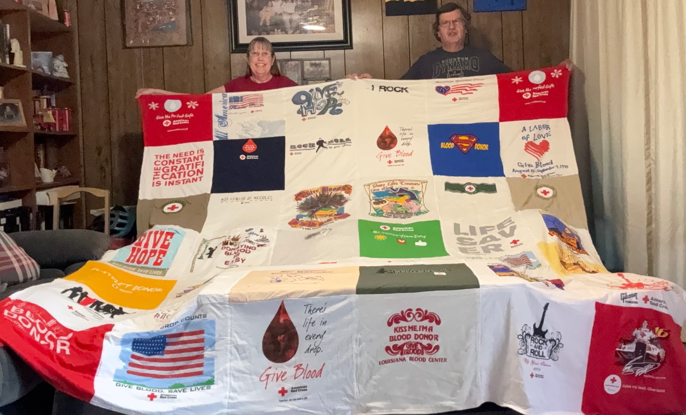 Two Red Cross blood donors holding up a quilt.