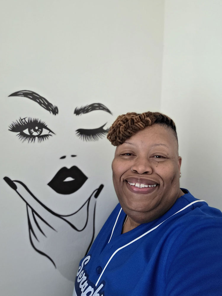 Chilata Brown stands in her new apartment, next to an artistic drawing of a face on the wall.