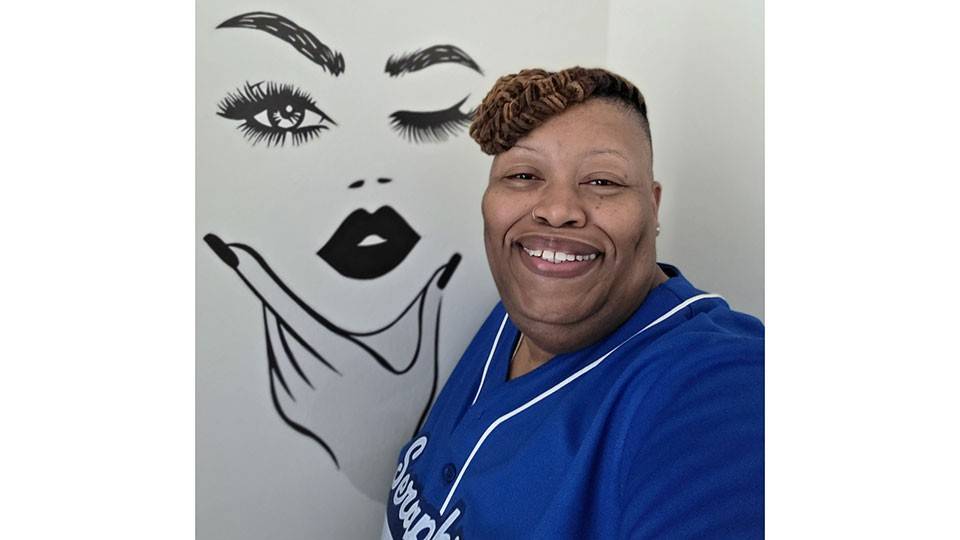 Chilata Brown stands in her new apartment, next to an artistic drawing of a face on the wall.