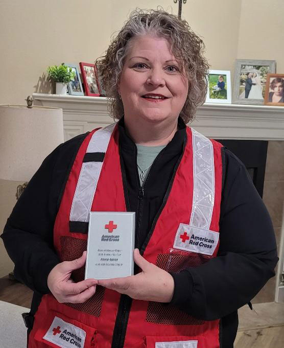 Cheryl Spiers wearing a Red Cross vest and holding an award.