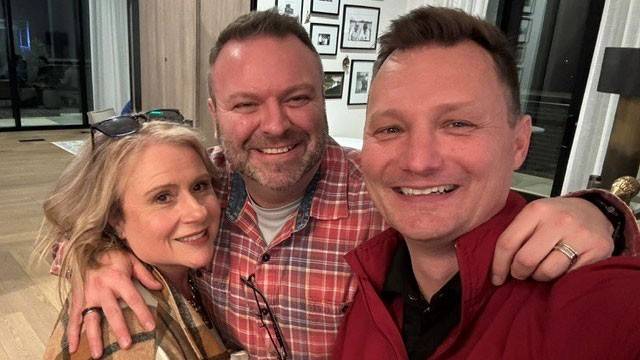 Craig Herr and two other people take a group picture inside a home.