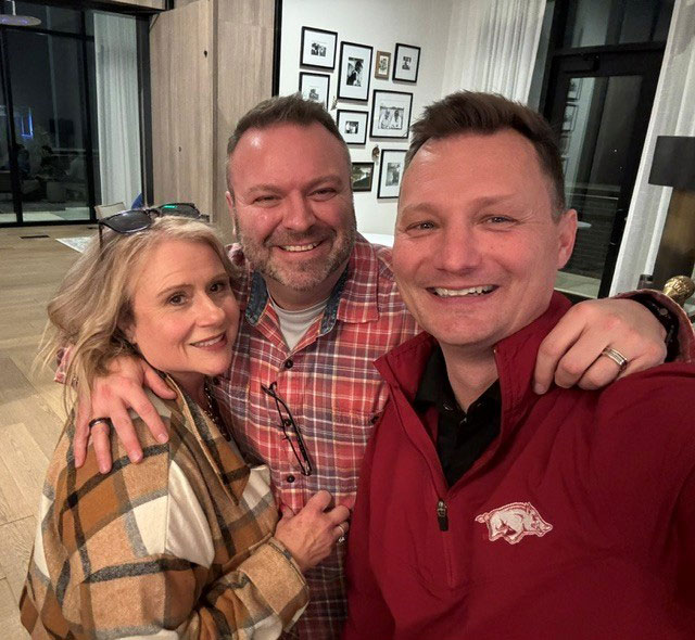 Craig Herr and two other people take a group picture inside a home.
