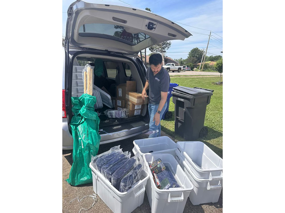 person loading bins with packaged items from the back of a mini van.