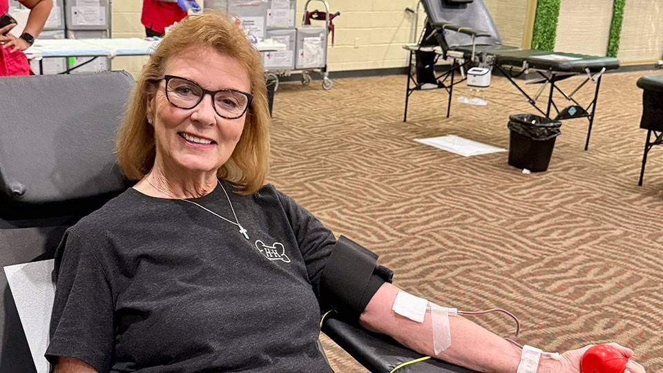Diane Holmes sitting in chair and donating blood.