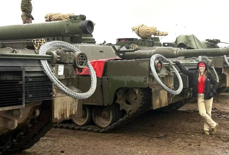 Jill Eaves, SAF regional program manager for the Red Cross Missouri-Arkansas Region, stands in front of a line of tanks at a NATO training base where she was deployed to work with U.S. troops. (Red Cross photo)