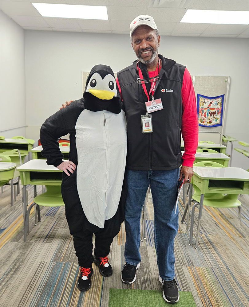 Henry Childress standing next to the prepare with pedro penguin mascot.