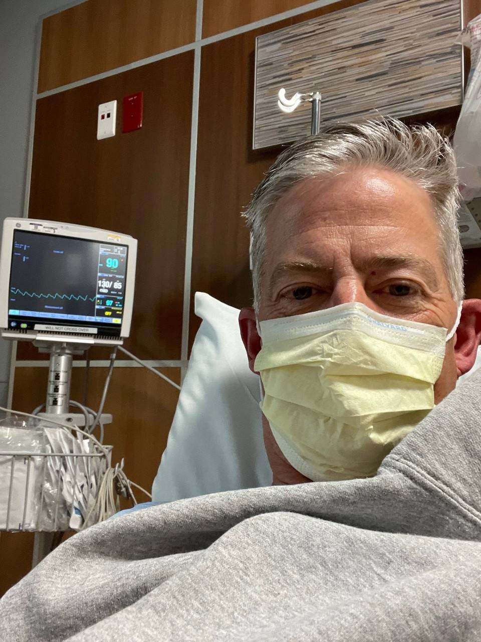 man laying in hospital bed wearing a mask