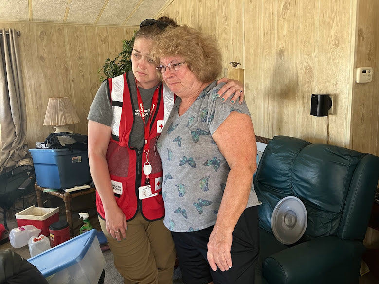 Red Crosser Lori consoles a resident in their living room.