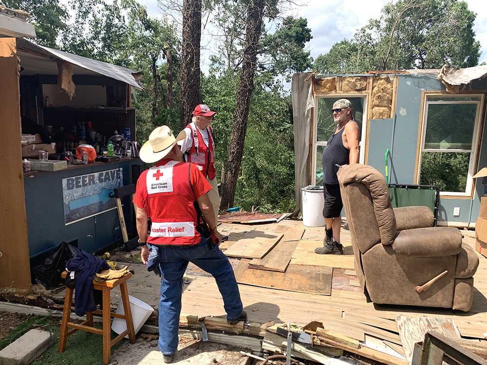 Two Red Cross volunteers talk with John Molz in demolished home