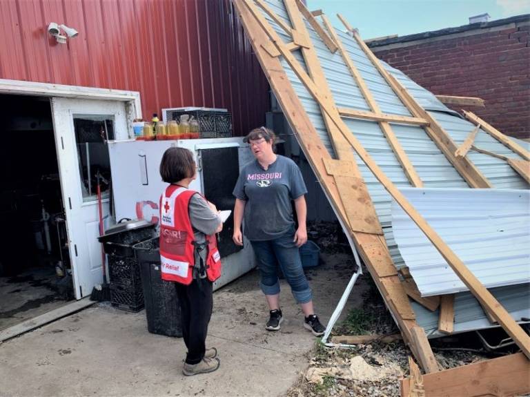 A couple of people standing next to a collapsed building