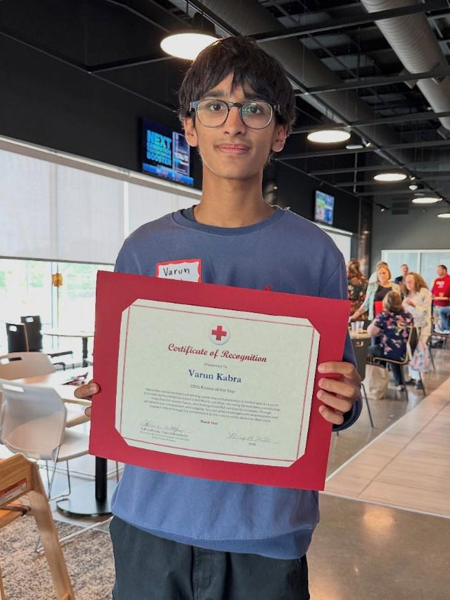 Varum Kabra wearing glasses and holding a Red Cross award.