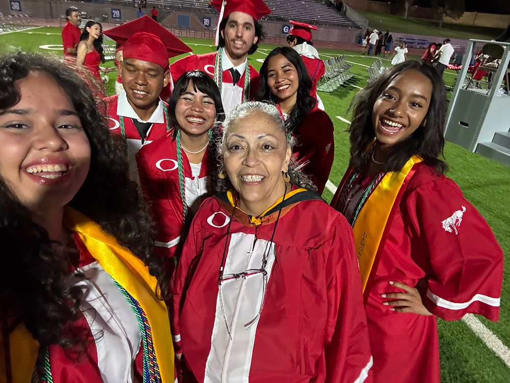Several Odessa High School students in graduation attire, including caps and robes, gathered together, smiling and celebrating their graduation.