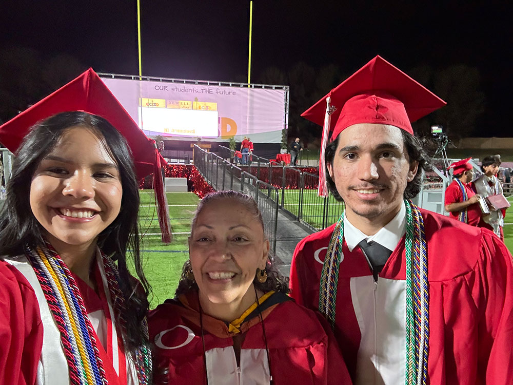 Three Odessa High School students in caps and gowns pose together, smiling for a celebratory photo.