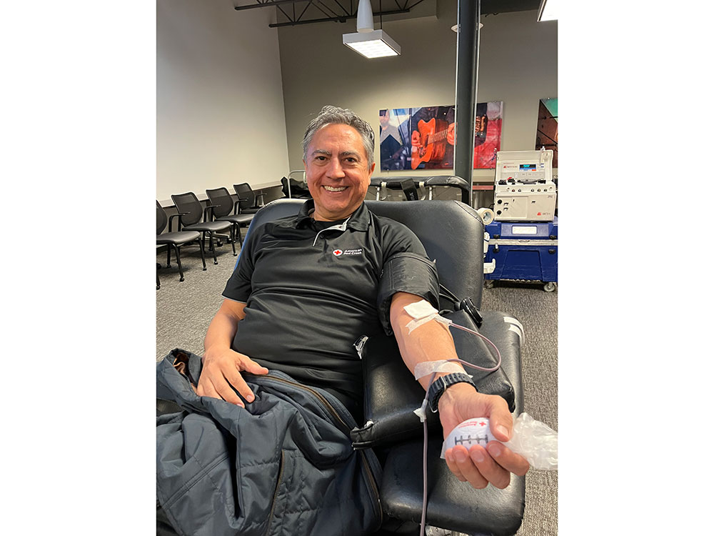 Javier Valdez sitting in a chair and donating blood.