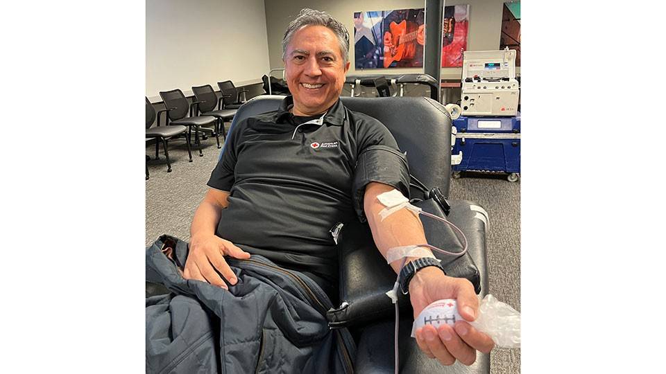 Javier Valdez sitting in a chair and donating blood.