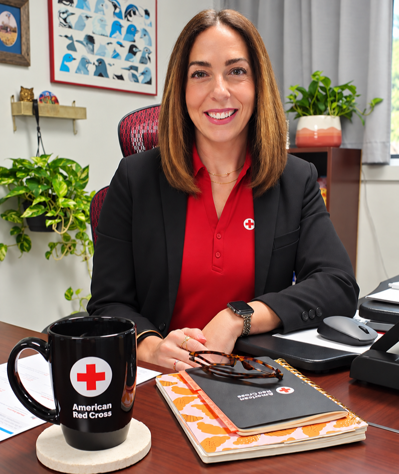 Liz Riley smiling wih a mug on her desk.