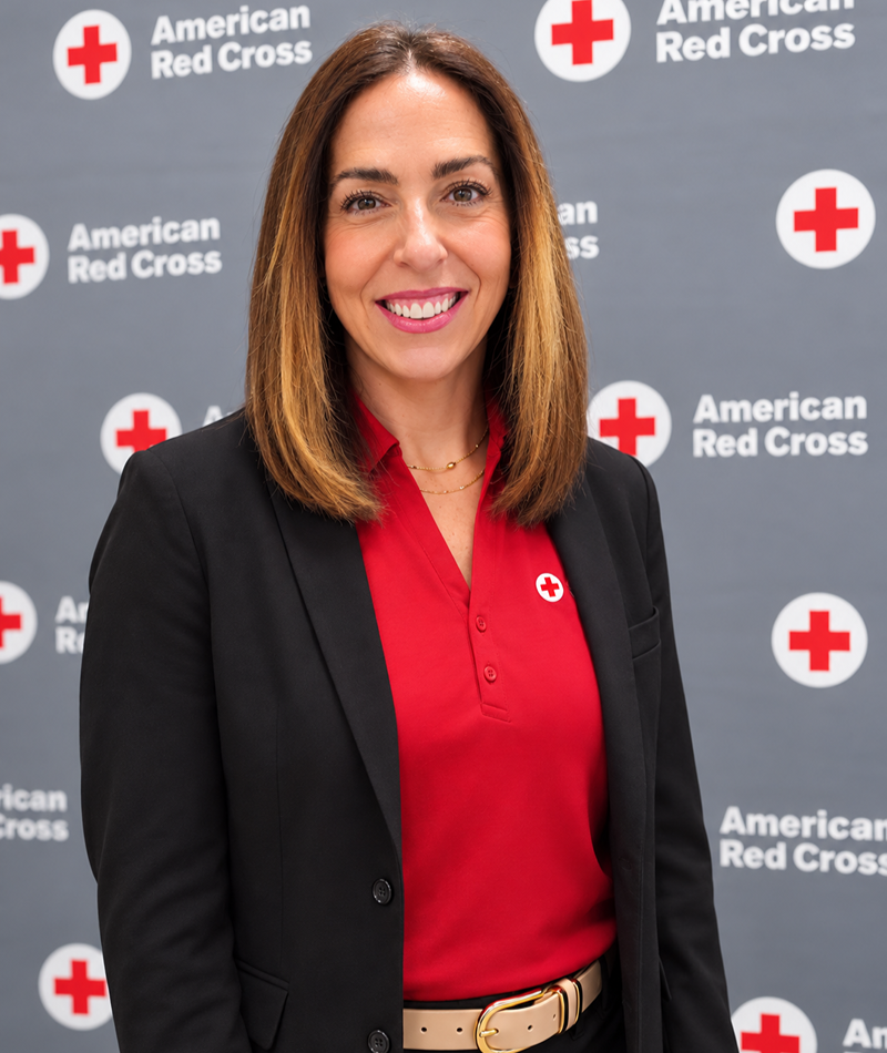 Liz Riley smiling with a Red Cross background.