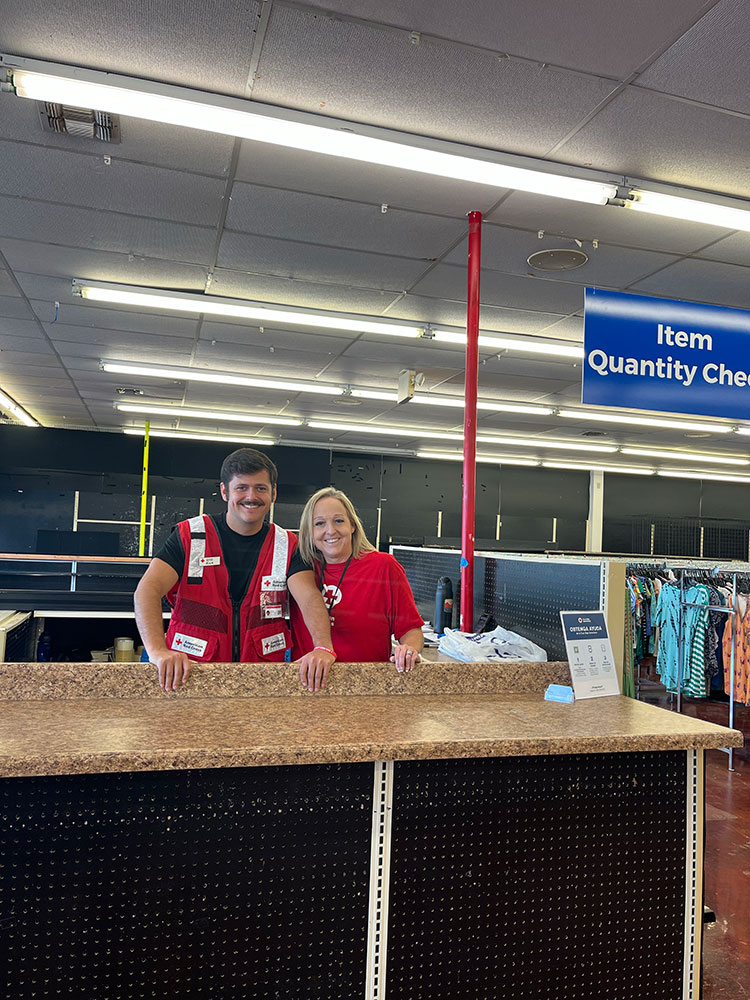 Nick Richardson in a Red Cross vest standing next to another volunteer and smiling for the camera.
