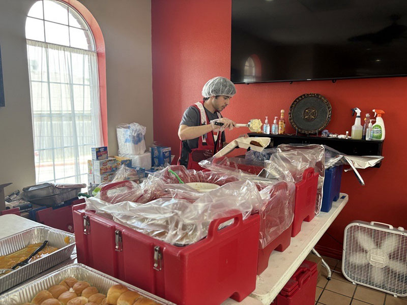 A Red Cross volunteer putting together plates of food in to-go containers.