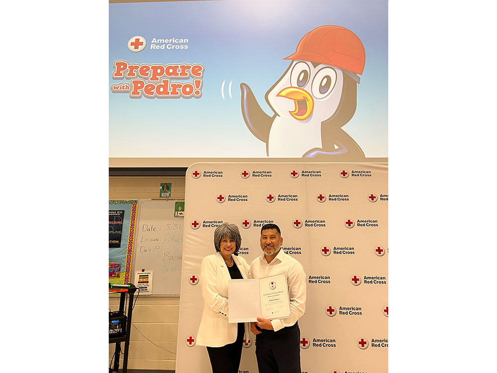 Two people pose with a certificate against an American Red Cross backdrop. Above them, a "Prepare with Pedro" slide features a penguin in a red hard hat.