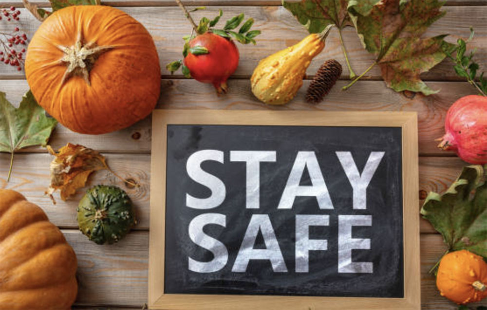 Pumpkins, squash, and other vegetables on a table with a sign that says stay safe.
