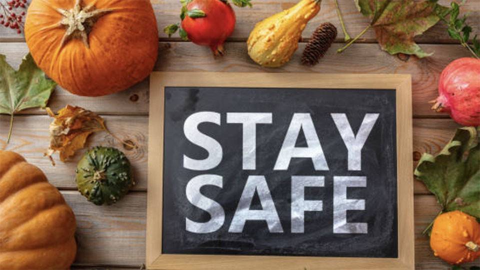 Pumpkins, squash, and other vegetables on a table with a sign that says stay safe.