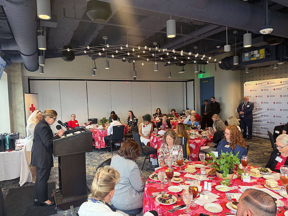 A group of people seated at tables in a well-lit room, engaged in conversation and activities.