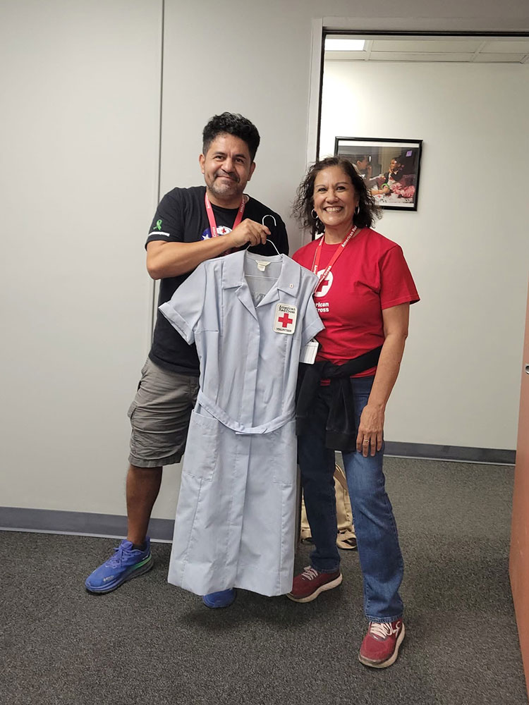 David Saucedo and another red cross volunteer posing with a vintage red cross nurse's dress.