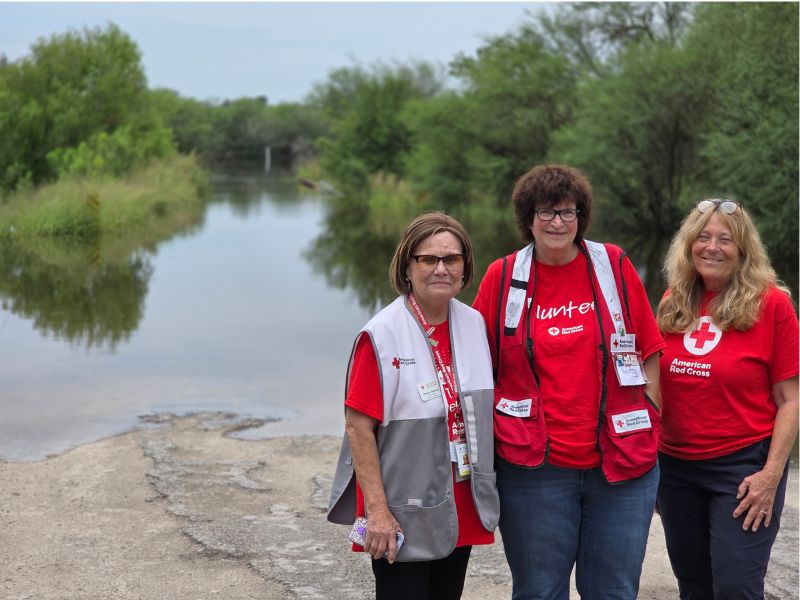 three red crossers stand in front of flooded area