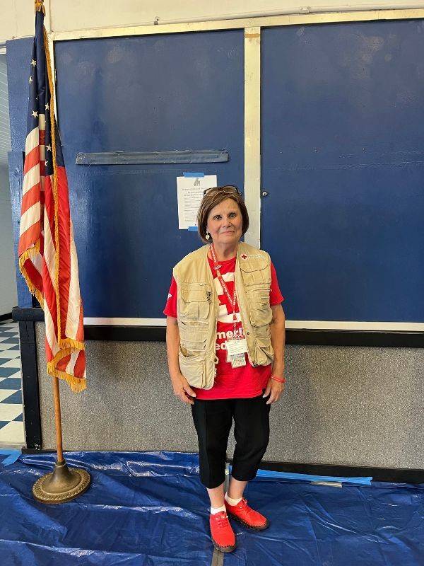 volunteer stands in front of blackboard with american flag in background