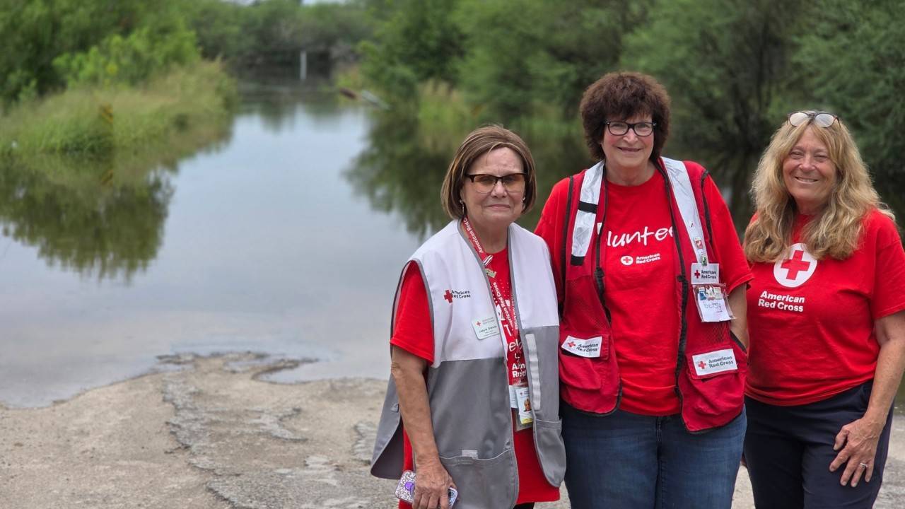 red crossers standing in front of flooded area