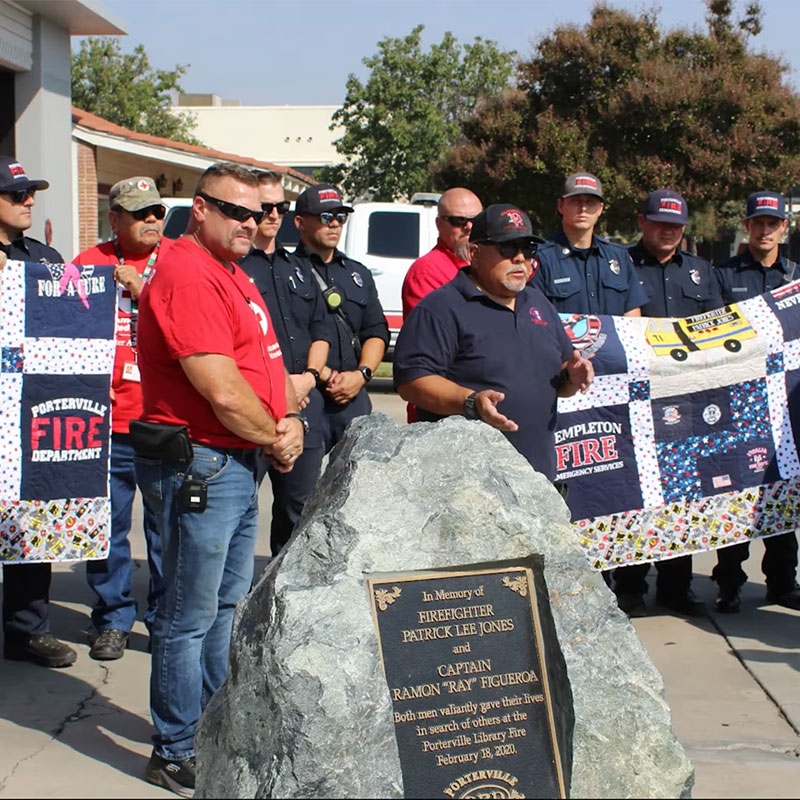 Firefighters holding quilts at event.