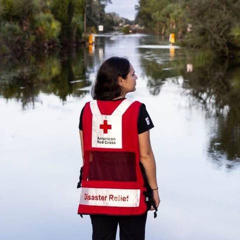 Red Cross volunteer looking at flooded road.