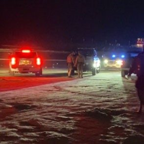 Law enforcement with vehicles on beach at night.