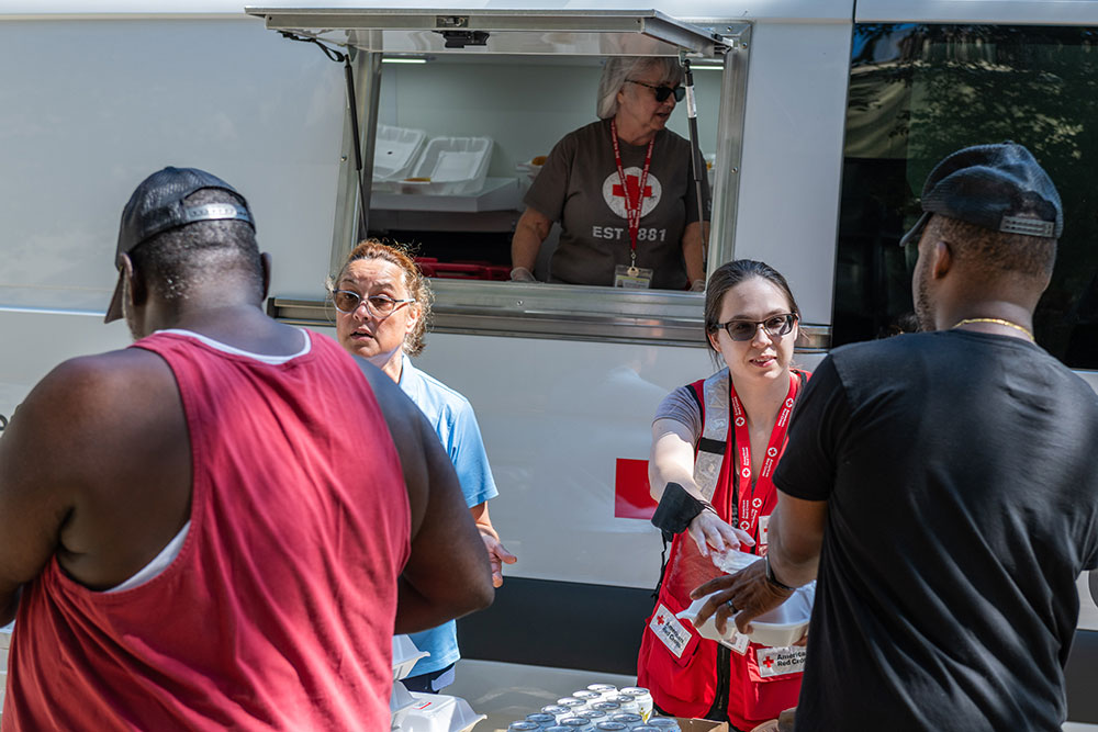 American Red Cross volunteers hand food to local residents.