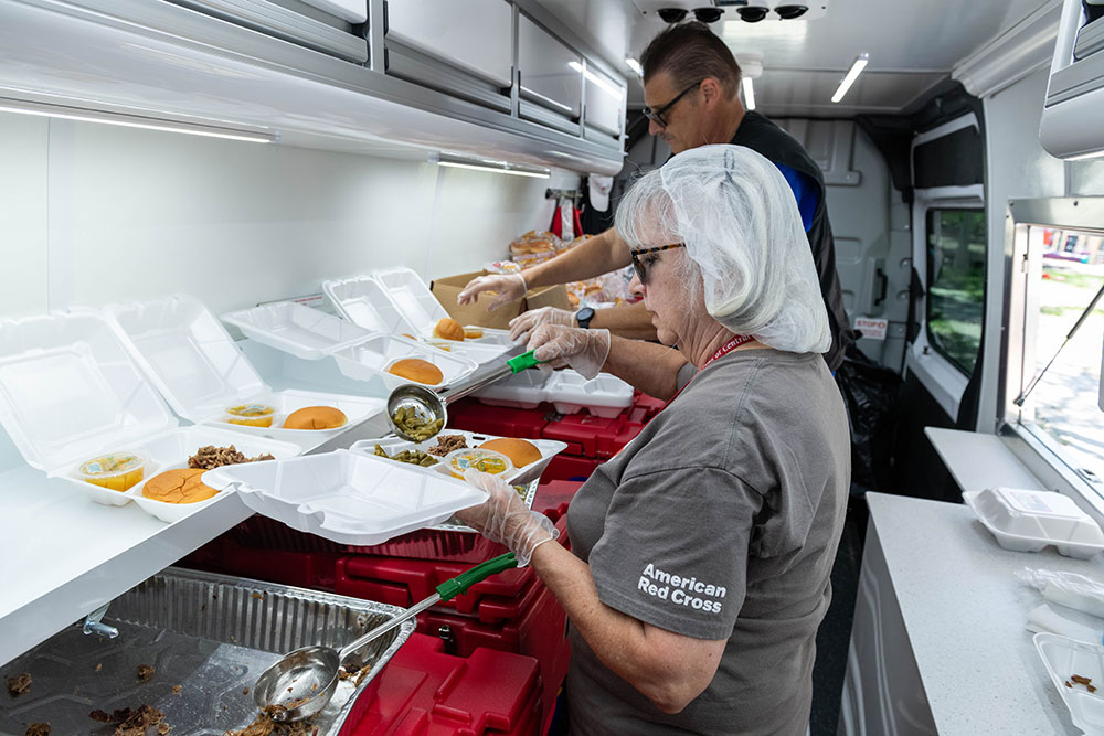 American Red Cross volunteers in food truck dishing up food into to go containers.