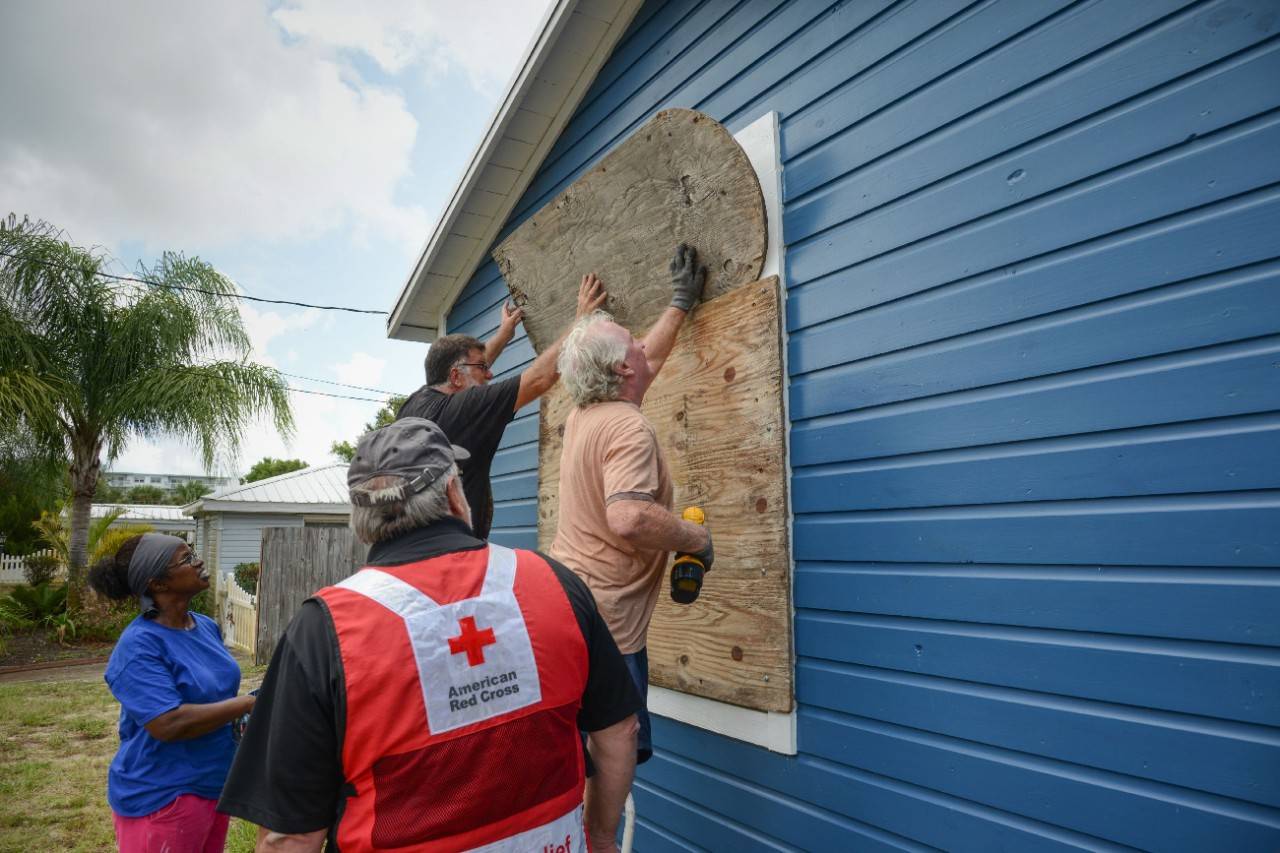August 31, 2019. Florida, Titusville.
American Red Cross volunteer Bob Wallace shares a moment with resident Robert Murphy (orange shirt) as he and his landlords, Jackie and Bruce Foster, board up windows in advance of Hurricane Dorian. Each of the boards had been carefully marked as to which window they should shutter, indicating that this was not the first storm for them to provide protection.
Photo by Daniel Cima/American Red Cross