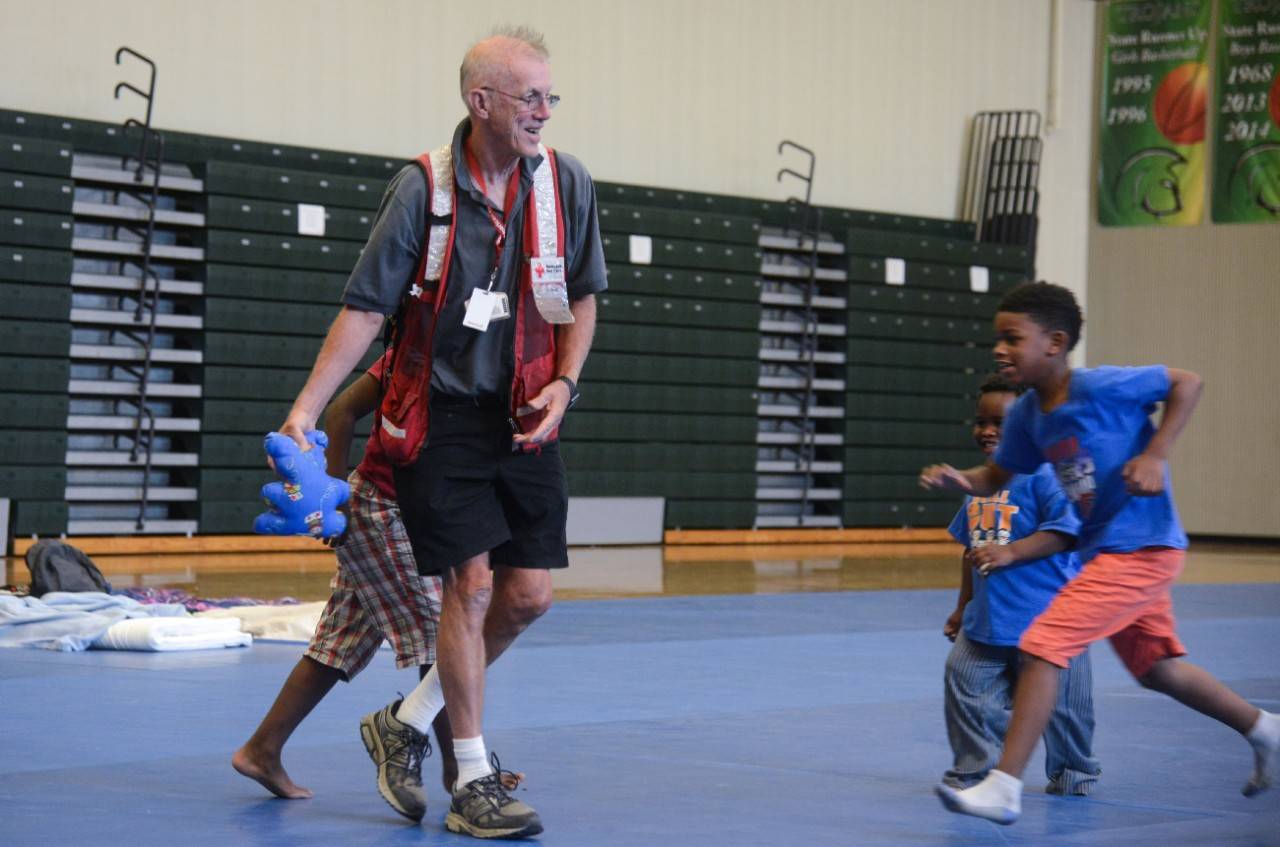 September 2, 2019. Orlando, Florida.
American Red Cross volunteer Tom Quinn plays a vigorous game of catch with some of the younger residents of the evacuation shelter located at Evans High School. Tom started volunteering as a disaster responder with the Red Cross about 5 years ago after retiring from an engineering position with Goodyear. Last year he deployed for three weeks to Saipan.  I love working in shelters and helping people,  Said Tom.
Photo by Daniel Cima/American Red Cross
