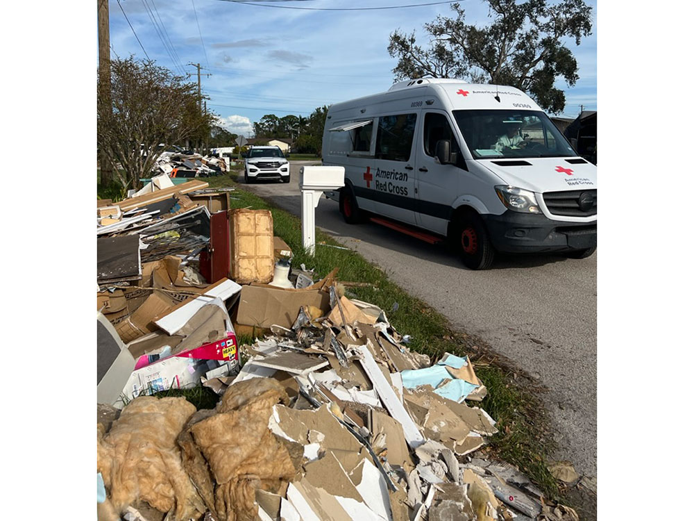 Red Cross Emergency Response Vehicle on street next to pile of debris.