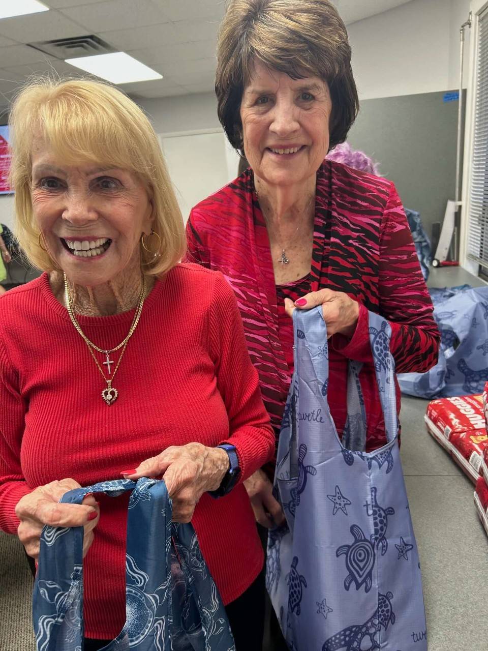 Shirley Taylor and Patricia Handly stuff reusable tote bags for the Red Cross Angels Bundles for Babies project.