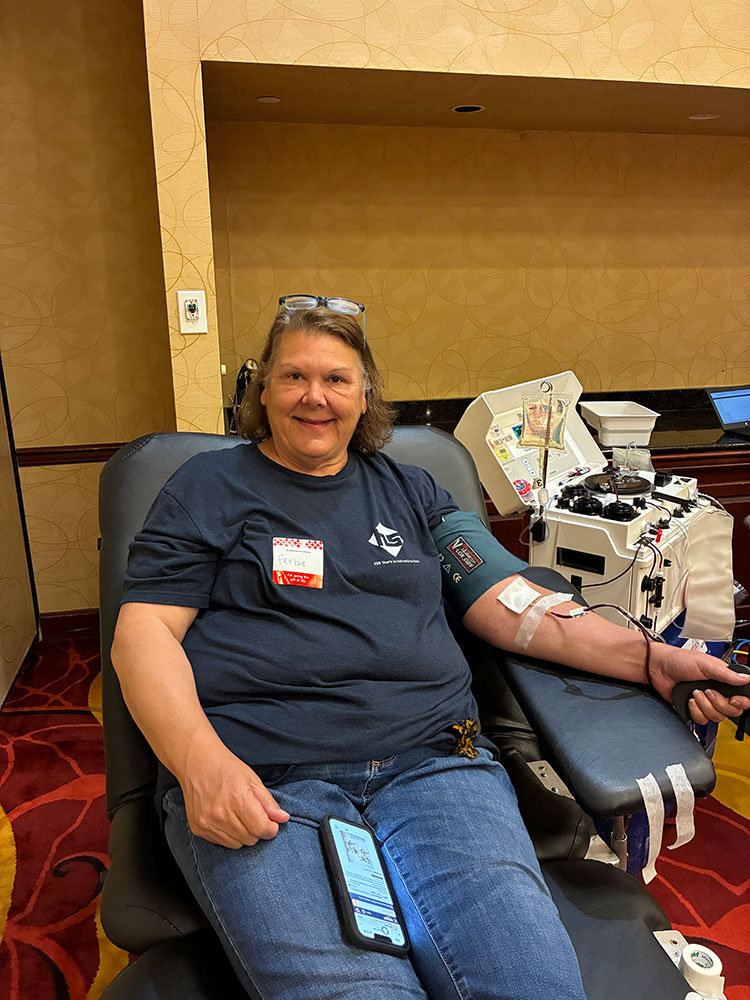 a woman sitting in a chair donating blood while smiling.