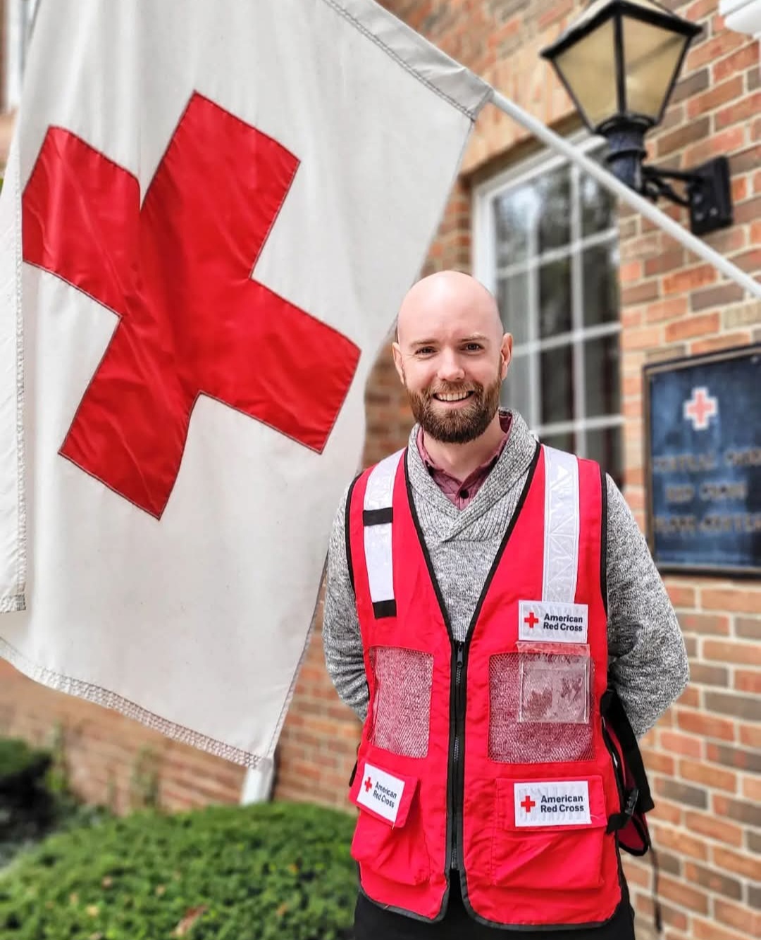 atticus garden standing next to red cross flag