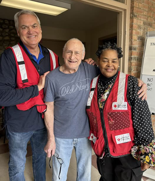 Stanley Shepherd with two red cross volunteers smile for picture.