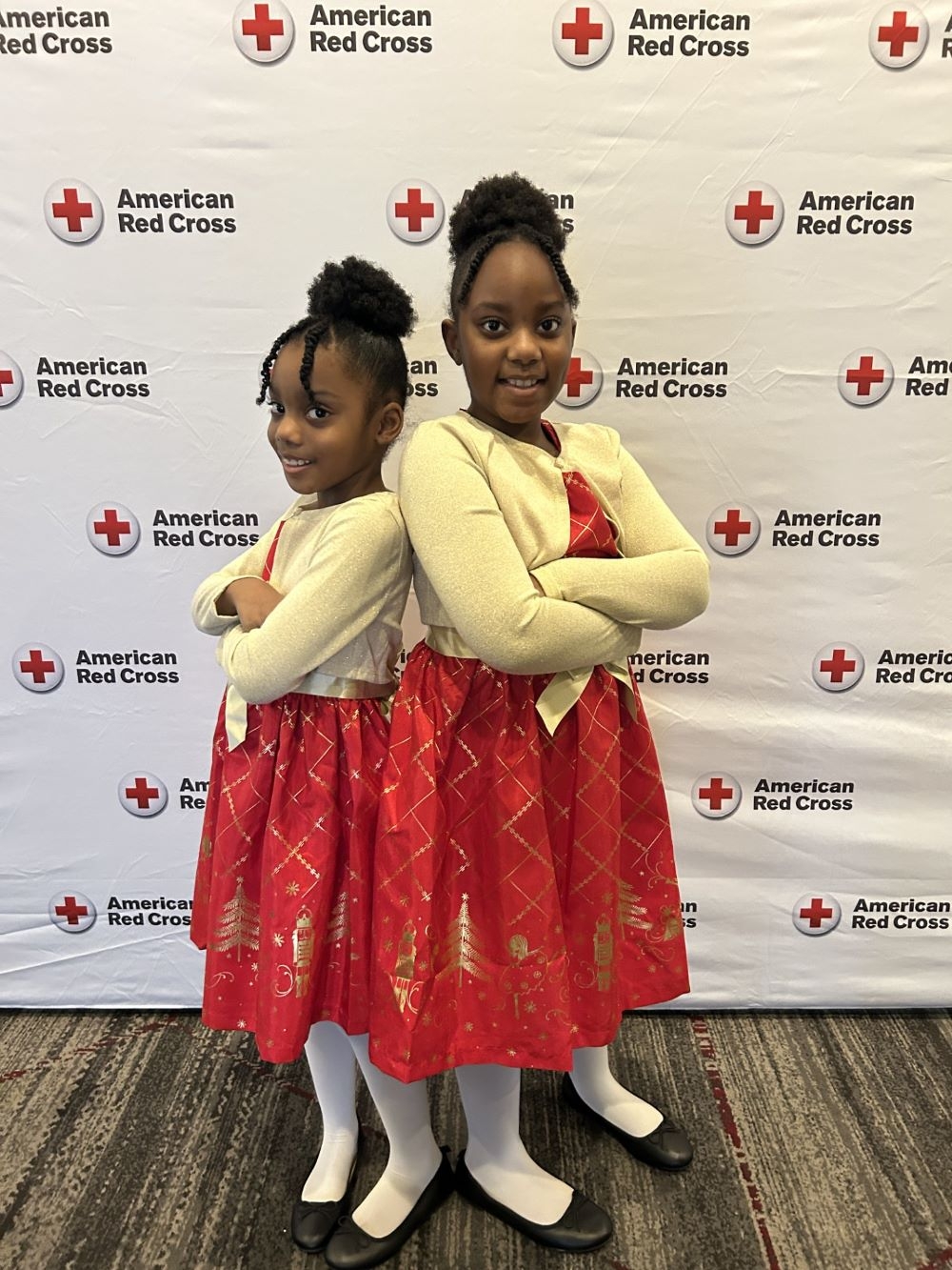 Cicelia and Brianna Dobson smiling in front of a American Red Cross banner