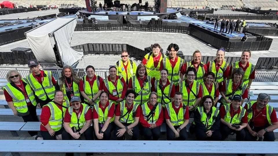 Group picture of the First Aid Services Team, all wearing safety vests, inside an empty stadium.