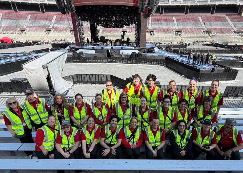 Group picture of the First Aid Services Team, all wearing safety vests, inside an empty stadium.
