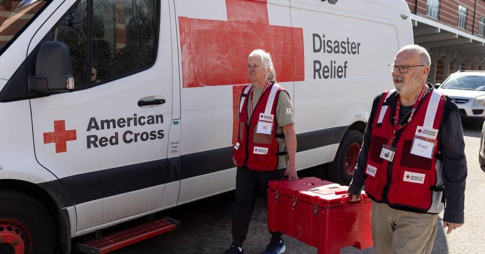 Two red cross volunteers carrying a red bag of supplies