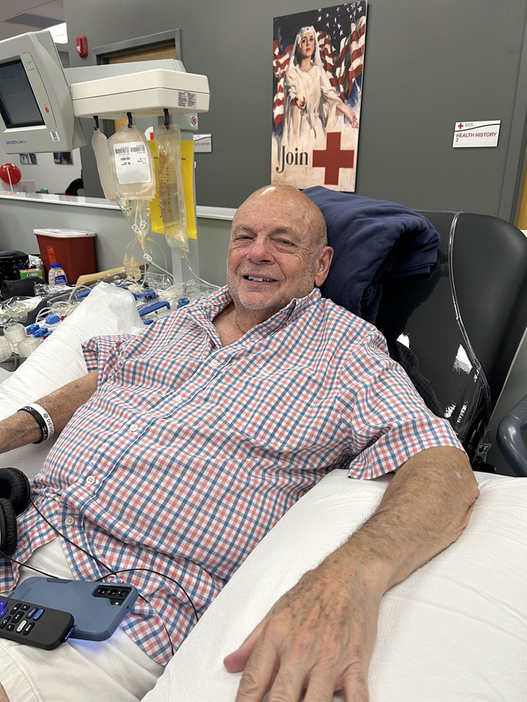 Mark Radel sitting in chair donating at the Red Cross Blood and Platelet Donation Center.